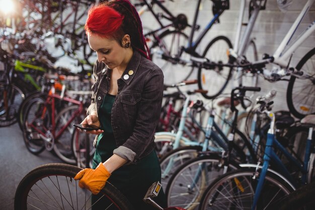 Mechaniker mit Handy während Fahrrad reparieren