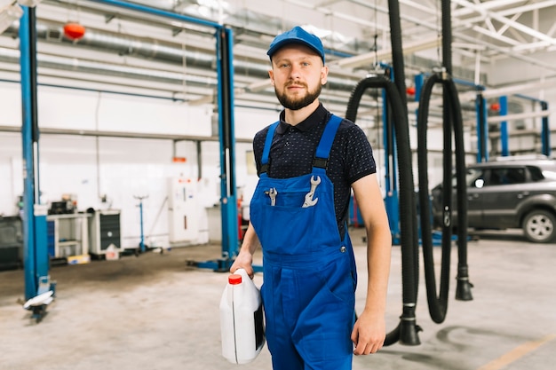 Mechaniker mit Ölkanne an der Autowerkstatt