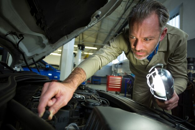 Mechaniker untersuchen ein Auto mit Lampe