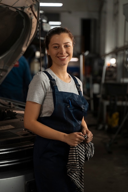 Mechanikerin, die in der Werkstatt an einem Auto arbeitet