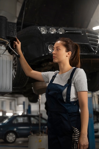 Kostenloses Foto mechanikerin, die in der werkstatt an einem auto arbeitet