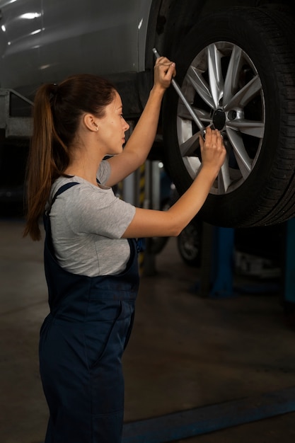 Mechanikerin, die in der Werkstatt an einem Auto arbeitet