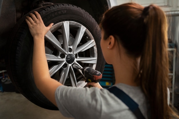 Mechanikerin, die in der Werkstatt an einem Auto arbeitet