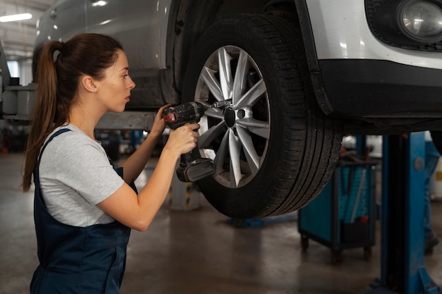 Mechanikerin, die in der Werkstatt an einem Auto arbeitet