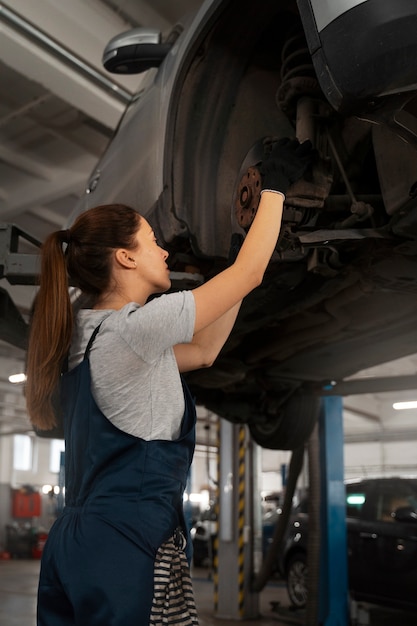 Mechanikerin, die in der Werkstatt an einem Auto arbeitet