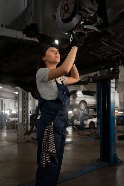 Mechanikerin, die in der Werkstatt an einem Auto arbeitet