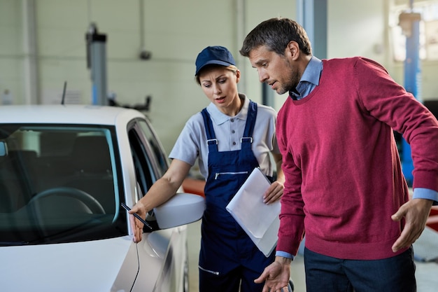 Mechanikerin und Autobesitzerin kommunizieren über Fahrzeugpanne in der Autowerkstatt