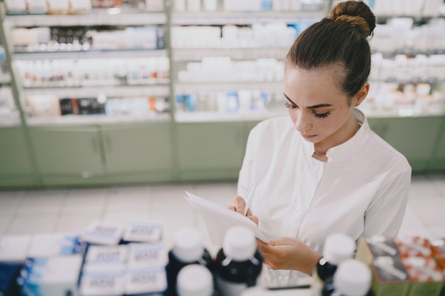 Kostenloses Foto medizin, pharmazie, gesundheitswesen und personenkonzept. apothekerin, die medikamente aus dem regal nimmt.