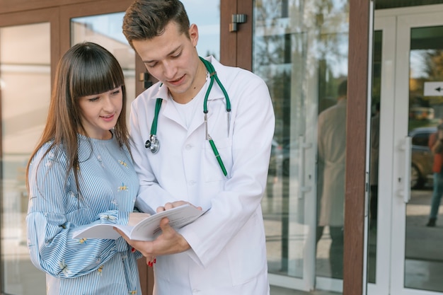 Mediziner und Patient mit Papieren an der Klinik