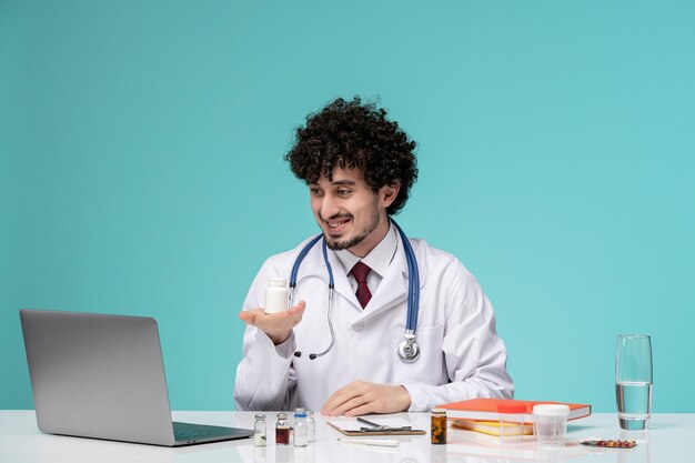 Medizinisch im Laborkittel junger ernster gutaussehender Arzt, der am Computer arbeitet und weiße Pillen hält
