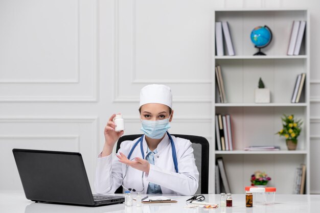 Medizinisch süßer Arzt in weißem Laborkittel und Hut mit Computer in der Maske