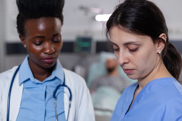 Medizinische krankenschwester, die sich mit einem afroamerikanischen praktiker die medizinische genesung ansieht
