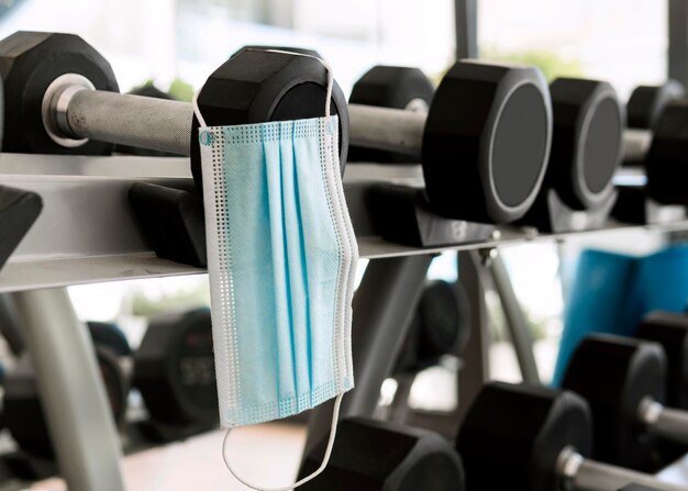 Medizinische Maske im Fitnessstudio, die an Gewichten hängt