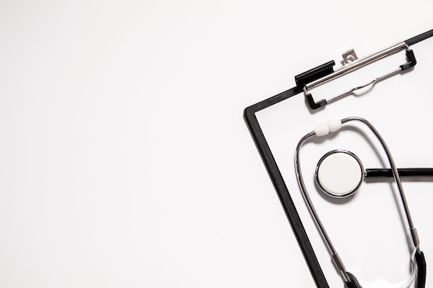 Medizinische Stethoskop oder Phonendoscope isoliert auf weißem Hintergrund ausgeschnitten. Stethoskop und Zwischenablage mit leeren weißen Blatt Papier und Kopie Raum. Medizinisches Konzept