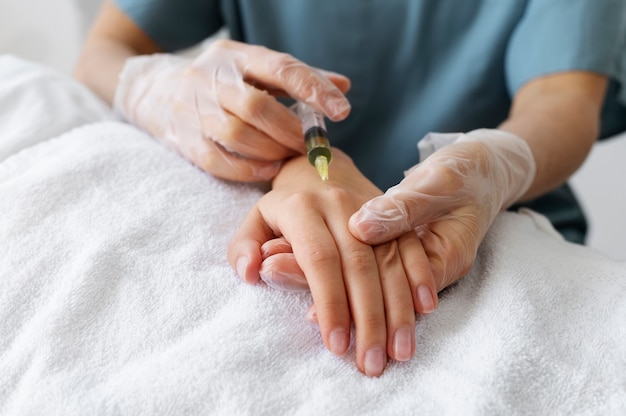 Medizinisches Fachpersonal mit niedrigem Winkel, das die Hand injiziert