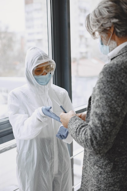 Kostenloses Foto medizinisches personal untersucht den senior. kontrolle vor dem betreten des gebiets mit einer epidemie covid-19.