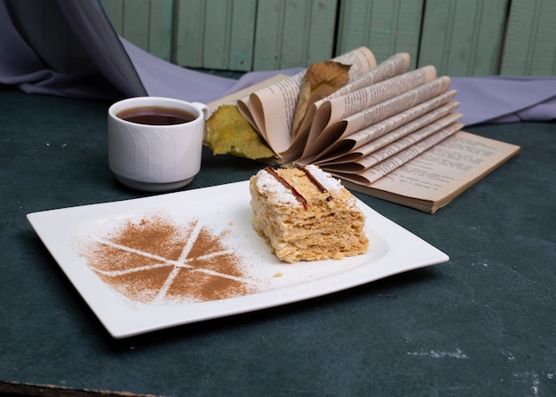 Medovik-Kuchen mit Kakaopulver und einer Tasse Tee.