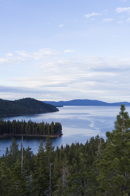 Kostenloses Foto meer umgeben von bewaldeten bergen unter einem blauen himmel