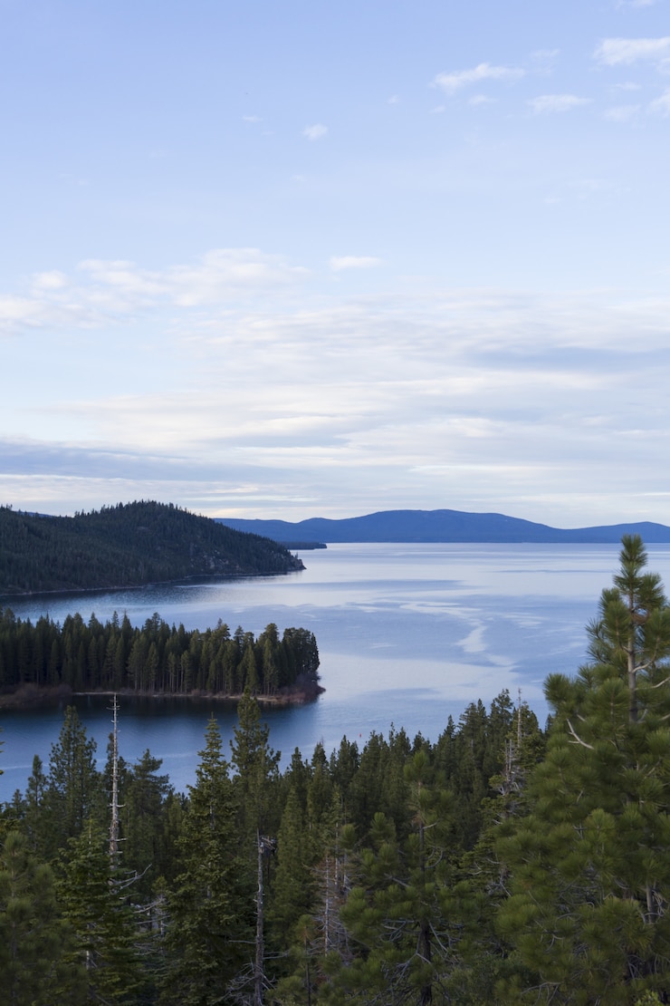 Kostenlose Foto meer umgeben von bewaldeten bergen unter einem blauen himmel