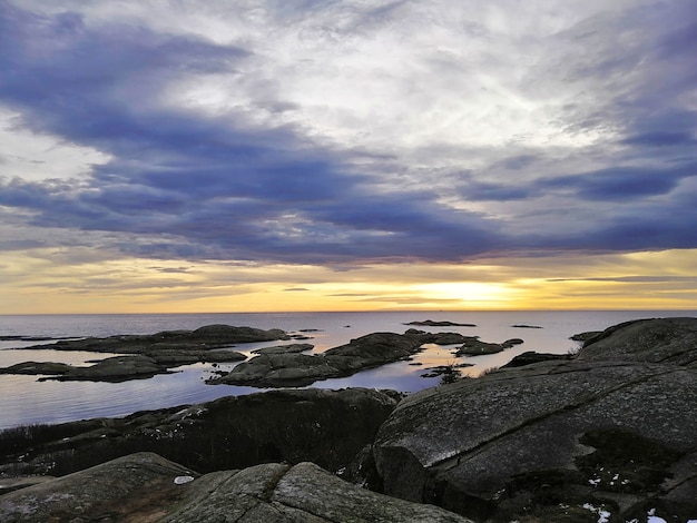 Meer umgeben von Felsen unter einem bewölkten Himmel während des Sonnenuntergangs in Rakke in Norwegen