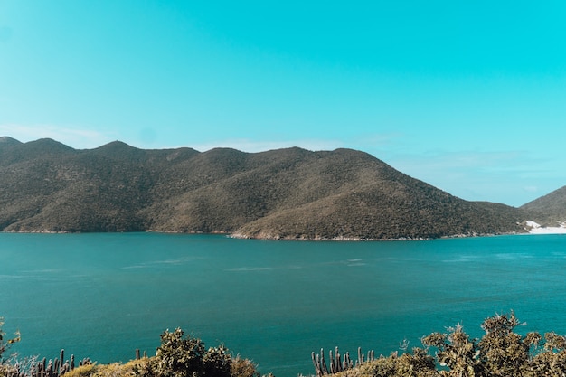 Meer umgeben von grünen Hügeln unter blauem Himmel und Sonnenlicht in Rio de Janeiro