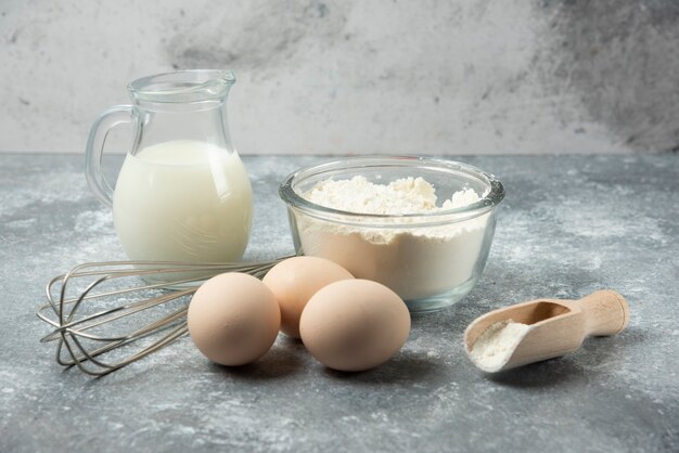 Mehl, Eier, Milch und Whisker auf Marmor.