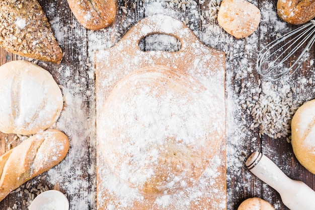 Mehl über dem Schneidebrett und verschiedene Brotsorten auf dem Tisch