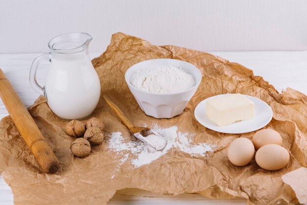 Mehl; Walnüsse; Eier; Käse; Nudelholz auf braunem zerknittertem Papier