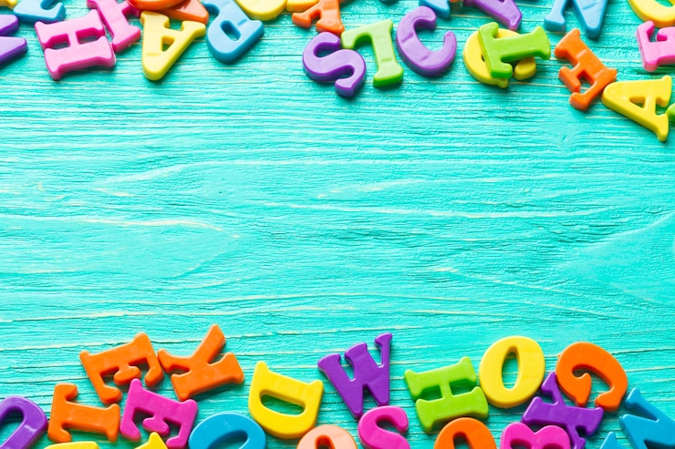 Kostenlose Foto mehrere farbige buchstaben auf holztisch