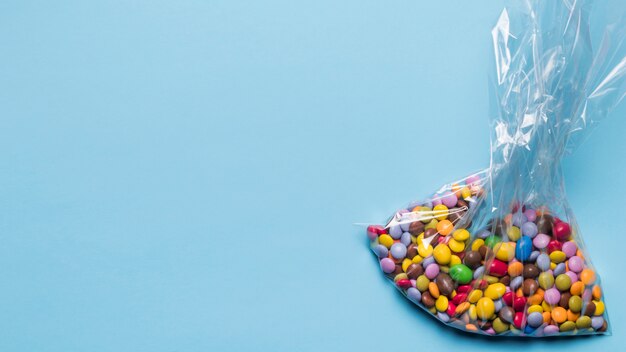 Mehrfarbige Edelsteinsüßigkeiten in der Plastiktasche auf blauem Hintergrund