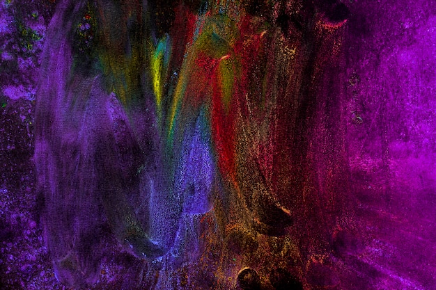 Mehrfarbige holi Farben befleckten mit der Hand auf schwarzem Hintergrund