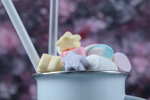 Mehrfarbige Marshmallows in einer blauen Metallic-Tasse.