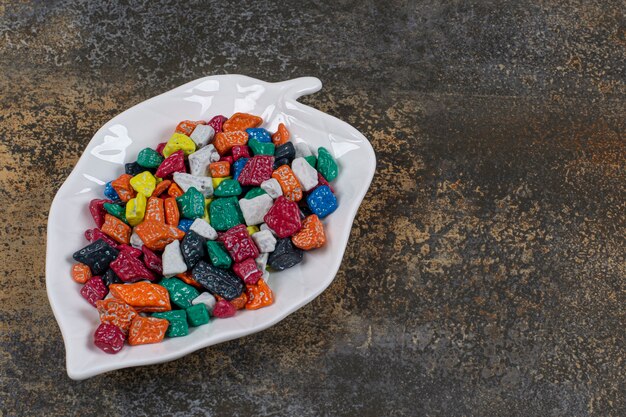 Mehrfarbige Steinbonbons auf blattförmigem Teller.