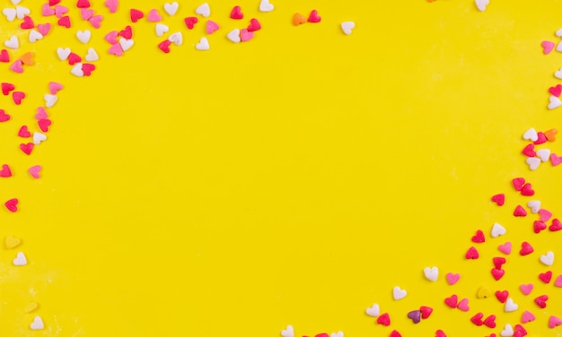 Mehrfarbige Süßigkeiten des Kopierraums der Draufsicht in der Form eines Herzens auf einem gelben Hintergrund