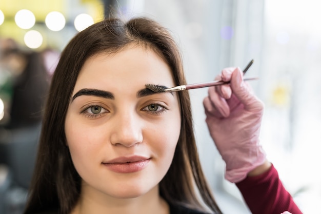 Meister macht die letzten Schritte im Make-up für das Modell mit grünen Augen