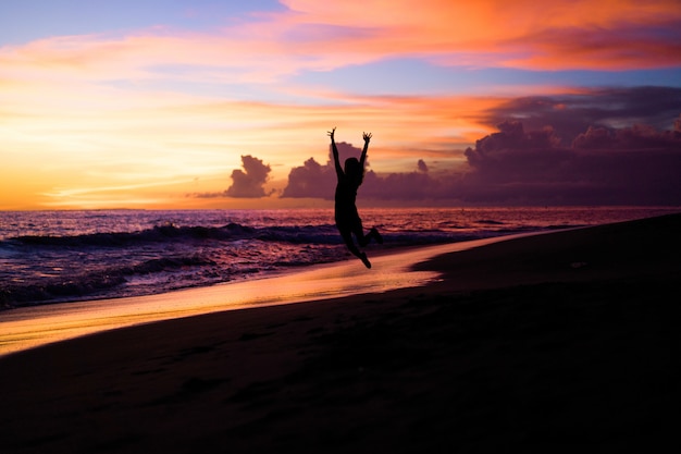 Menschen am Strand bei Sonnenuntergang. das Mädchen springt
