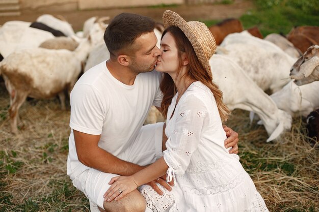 Menschen auf einem Bauernhof. Paar mit einer Ziege. Frau in einem weißen Kleid.