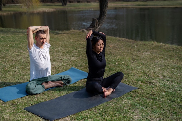 Kostenloses Foto menschen, die draußen yoga praktizieren