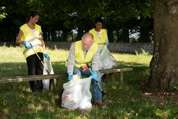 Kostenloses Foto menschen, die gemeinnützige arbeit leisten, indem sie müll in der natur sammeln