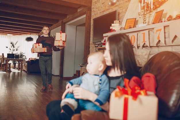 Menschen, die Geschenke, während seine Frau mit einem Baby auf einem Sofa sitzt