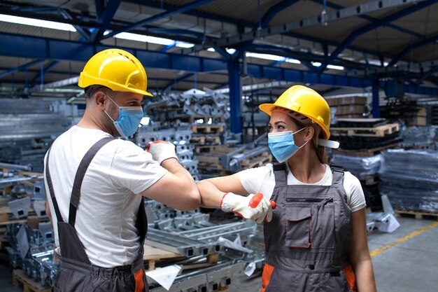 Menschen, die in der Fabrik arbeiten, berühren sich mit Ellbogen und grüßen wegen Koronavirus und Infektion