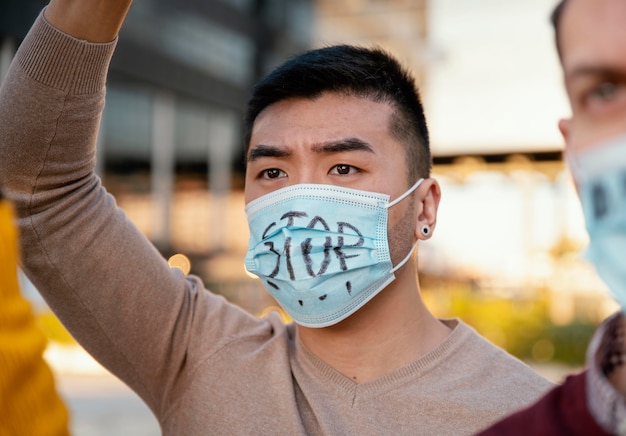 Menschen, die mit Gesichtsmasken protestieren, schließen sich