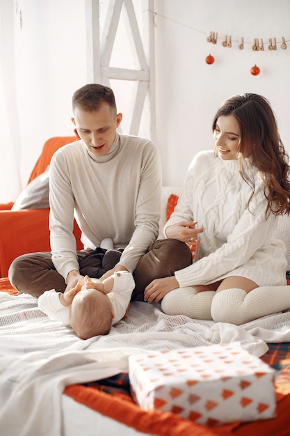 Menschen, die sich auf Weihnachten vorbereiten. Leute, die auf einem Bett sitzen. Familie ruht in einem festlichen Raum.