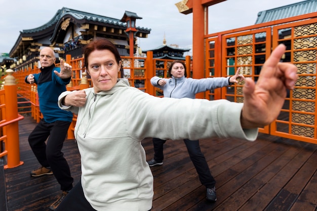 Kostenloses Foto menschen, die tai chi außerhalb der seitenansicht praktizieren