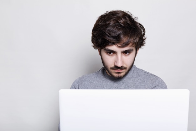 Menschen, Emotionen, Technologie, Bildung. ernsthafter stilvoller Kerl mit trendigem Bart, der mit seinem Laptop arbeitet.