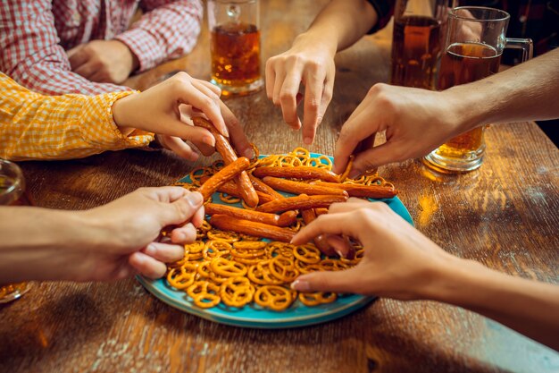 Menschen, Freizeit, Freundschaft und Kommunikationskonzept. glückliche Freunde trinken Bier, reden und klirren an der Bar oder im Pub.