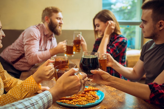 Kostenloses Foto menschen, freizeit, freundschaft und kommunikationskonzept. glückliche freunde trinken bier, reden und klirren gläser an der bar oder im pub und machen selfie-foto per handy.