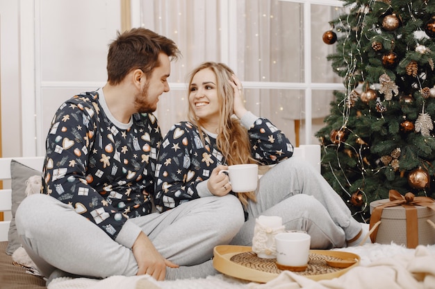 Menschen in einer Christman-Dekoration. Mann und Frau in einem identischen Pyjama. Familie auf einem Bett.