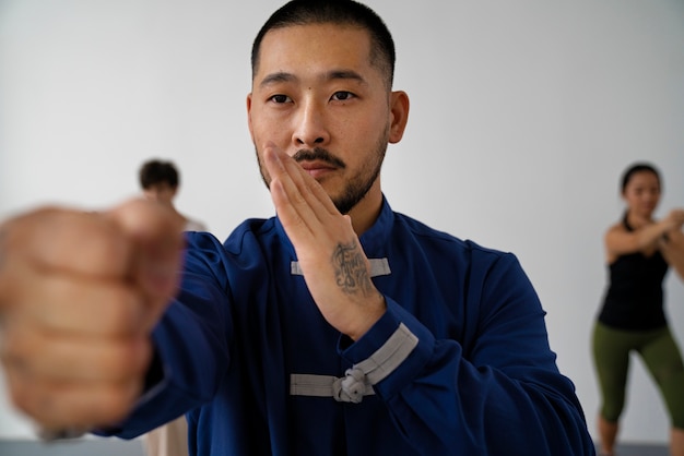 Kostenloses Foto menschen mit vorderansicht, die drinnen tai chi praktizieren