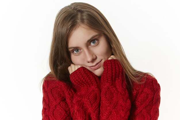 Menschen, Stil, Mode, Schönheit, Jahreszeiten und Kleidungskonzept. Isoliertes Bild der herrlichen modischen jungen Frau mit positivem glücklichem Lächeln, gekleidet im trendigen warmen Strickpullover mit langen Ärmeln